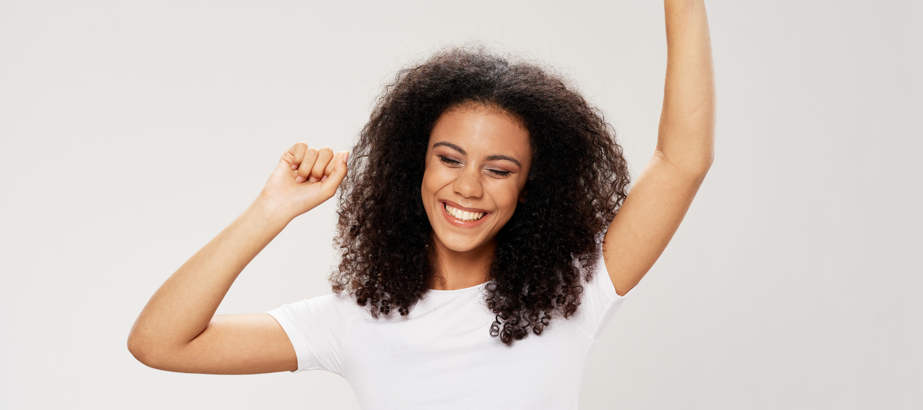 a woman with curly hair is smiling with her arms in the air