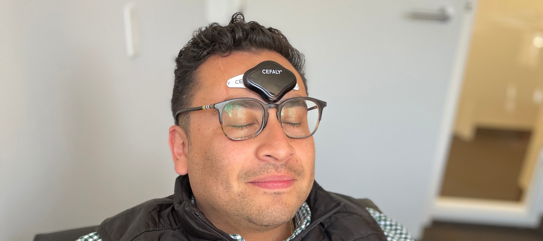 person Wearing CEFALY device, eyes closed for therapeutic effect